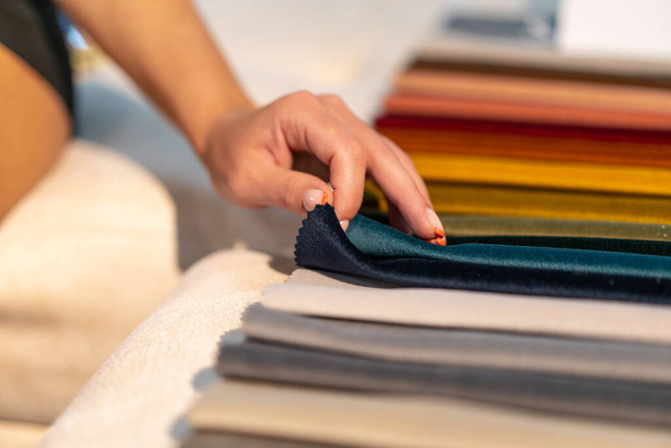 La donna sceglie il tessuto sul divano. Contesto dell'industria tessile. Catalogo dei tessuti - Foto, immagini