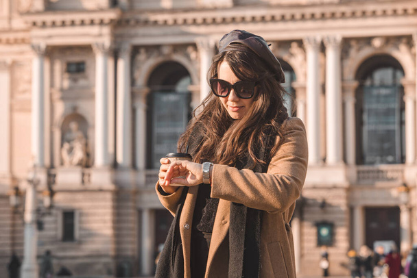 コートのスタイリッシュな豪華な女性の肖像屋外でコーヒーを飲みながらコピースペースに行く - 写真・画像