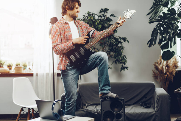 Man playing electric guitar and recording music into laptop - Fotó, kép