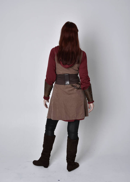 Retrato completo de niña vestida con traje medieval. Posar de pie con la espalda a la cámara, aislado sobre un fondo gris estudio. - Foto, Imagen