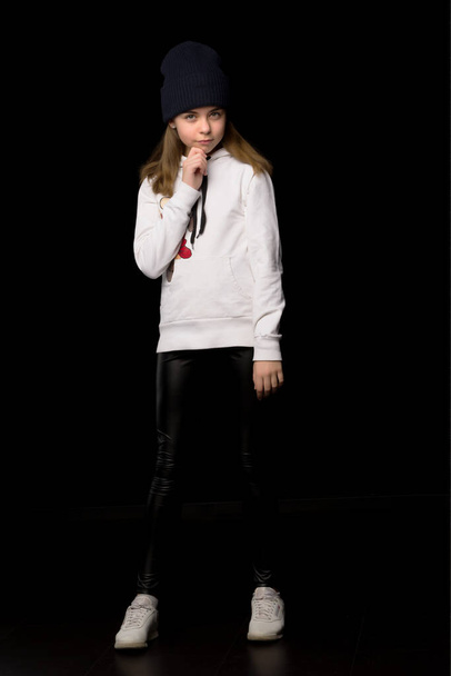 Little girl teenager in a sports youth suit. On a black backgrou - Fotó, kép