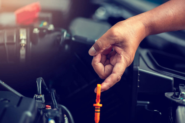 Selective focus to hand is checking the oil level in car engine. Mechanic checking car engine or vehicle. Check and maintenance car with yourself. Service and maintenance vehicle. - Photo, Image