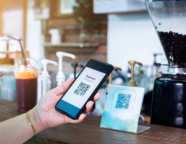 Customer hand using smart phone to scan Qr code payment tag  with blurry coffee grinder in coffee shop to accepted generate digital pay without money. Qr code payment concept. - Photo, Image