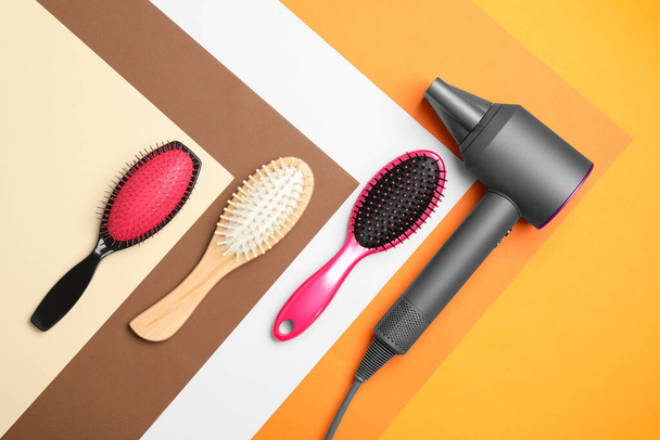 Hair dryer and different brushes on color background, flat lay. Professional hairdresser tool - Zdjęcie, obraz