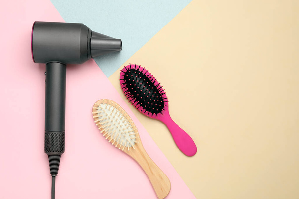 Hair dryer and different brushes on color background, flat lay. Professional hairdresser tool - Fotografie, Obrázek