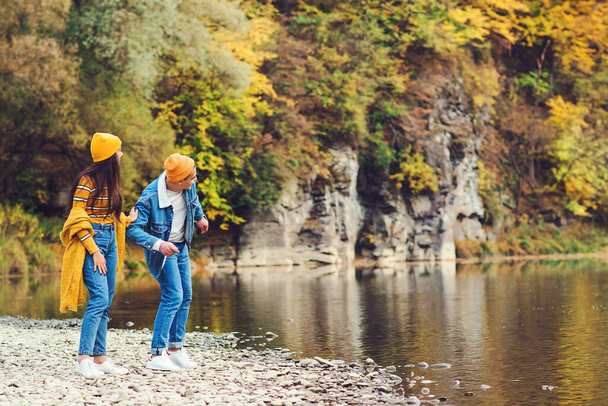 Lovely couple having fun together in nature. Love. Fashion couple enjoying autumn. Young people walking near lake in autumn. Fashion, lifestyle and autumn vacation. Stylish man and woman on a walk. - Photo, Image