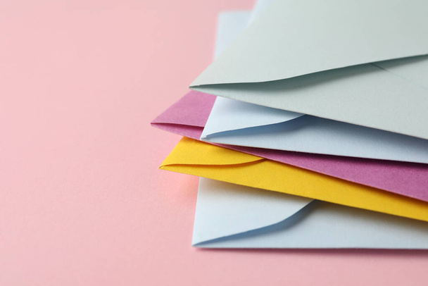 Montón de sobres de papel de colores sobre fondo rosa, primer plano. Espacio para texto - Foto, Imagen