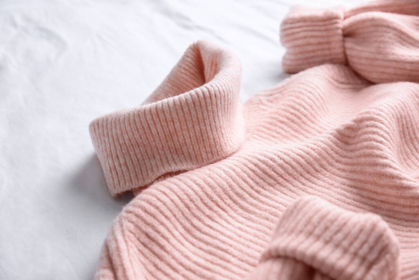 Pink warm sweater on white crumpled fabric, closeup - Фото, зображення