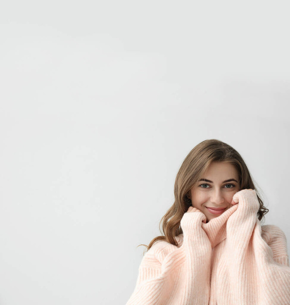 Beautiful young woman wearing warm pink sweater on light background. Space for text - Fotoğraf, Görsel