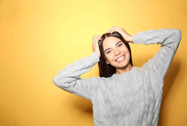 Happy young woman wearing warm sweater on yellow background  - Valokuva, kuva