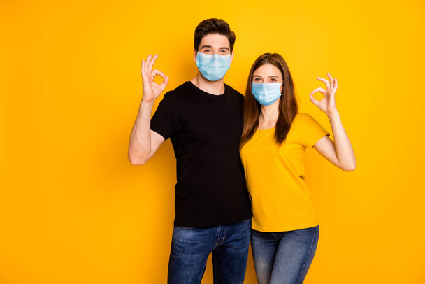 Portrait of his he her she nice attractive healthy couple showing ok-sign embracing wearing safety mask stop mers cov disease infection prevention isolated vibrant yellow color background - Foto, imagen