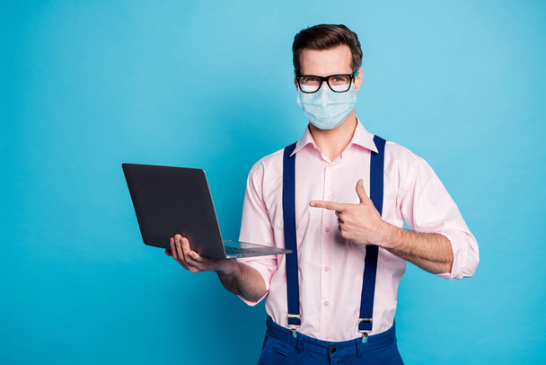 Portrait of his he attractive healthy guy wearing gauze safety mask showing using laptop stay home stop influenza mers cov social distance pandemia isolated bright vivid blue color background - Foto, imagen