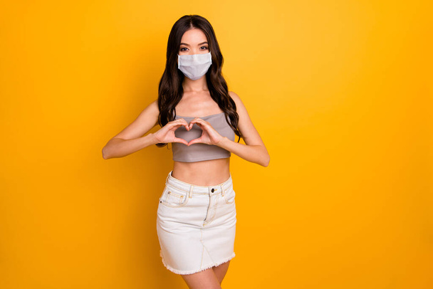 Portrait of her she nice attractive brunette girlfriend showing heart shape sign wearing safety gauze mask stop mers cov contamination isolated bright vivid shine vibrant yellow color background - Zdjęcie, obraz