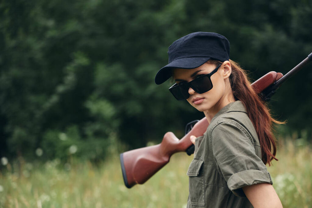Donna soldato Shotgun occhiali da sole da caccia tuta verde alberi verdi  - Foto, immagini