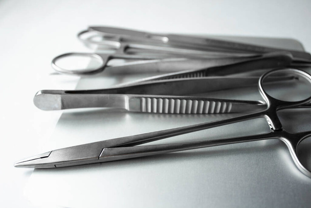 Chirurgische Instrumente auf Metalltablett. Skalpell, Klemme, Schere, chirurgische Pinzette auf weißem Hintergrund. Medizinische Instrumente - Foto, Bild
