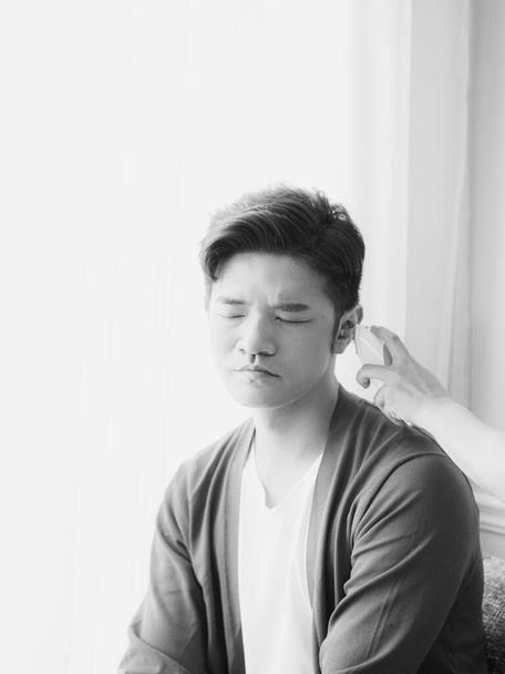 Joven asiático hombre usando máscara quirúrgica y el uso de termómetro de oído - Foto, imagen