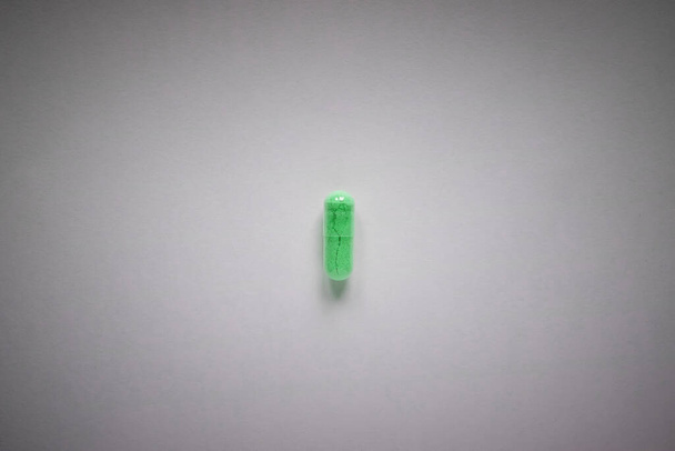 one green pill on a plain background - Foto, Imagem