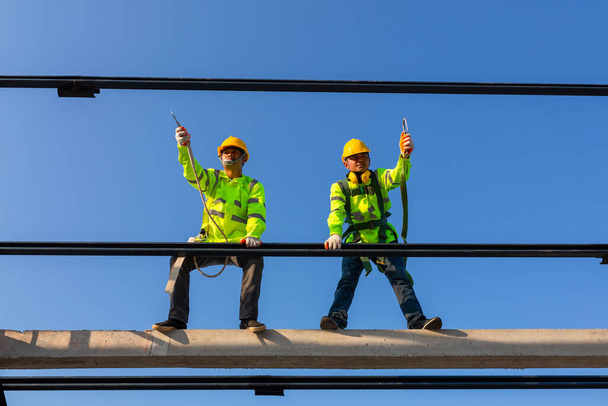 Equipo de altura de seguridad en el sitio de construcción; El trabajador asiático usa equipo de altura de seguridad para instalar el techo. Dispositivo anticaídas para trabajador con ganchos para arnés de seguridad. - Foto, Imagen