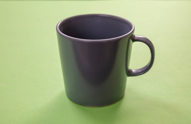Pastel yeşil arka planda kahve fincanı. Sıcak içecek kupası maketi. Gri kahverengi renkli boş bardak, kabzası reklam, damgalama şablonu - Fotoğraf, Görsel