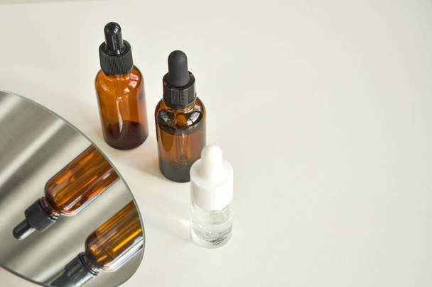Spa cosmetics in brown glass bottles on a white table. Beauty blogger, salon therapy, branding layout, minimalism concept. Top view, copy space - Foto, Bild