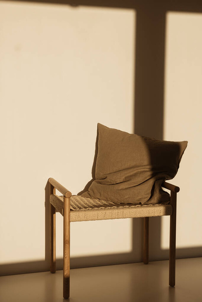 Oreiller sur banc en osier dans les ombres du soleil sur le mur. Concept de design intérieur minimal - Photo, image