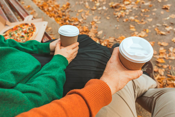 コーヒーを片手にマグカップを持ち上げるカップル。秋の暖かい日 - 写真・画像