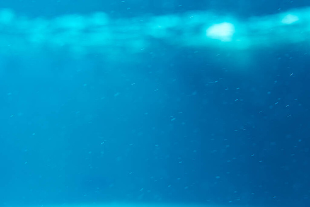Zomer. Textuur van het wateroppervlak. Onderwaterachtergrond. Golffecten. Blauwe onderwereld. Oceaan, zee. Duiken. Blauwe zee zwembad water. Onderaanzicht. - Foto, afbeelding