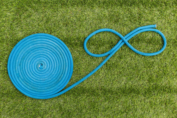 blue rope forming the symbol of infinity on the green grass - Foto, Imagen