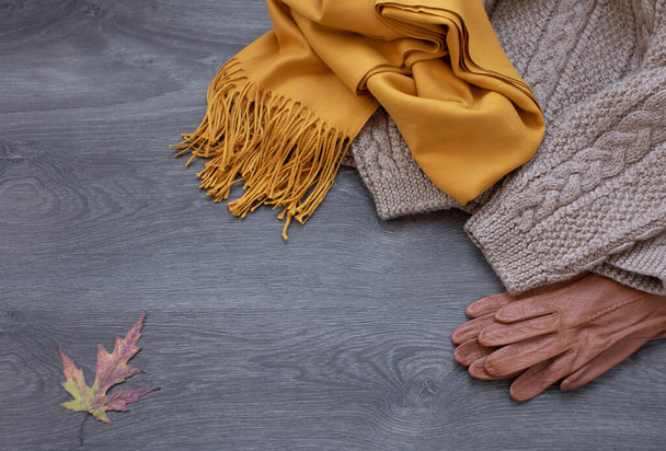 Autumn composition. Gloves, brown sweater, yellow scarf, plaid on wooden background. Flat lay, top view, copy space. Selective focus. - Fotoğraf, Görsel