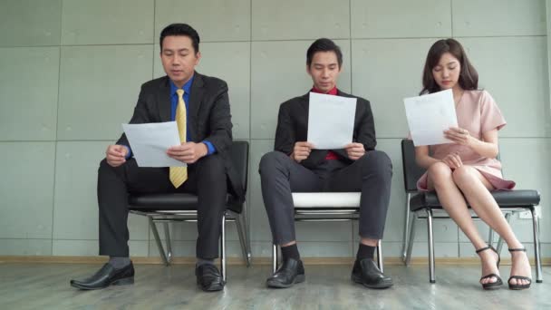  Jobless business people applicants group sitting in chairs in queue line row waiting for their turn company job interview. they look stressed and restless because they need a job in a vacancy, human resources, recruiting and employment concept - Footage, Video