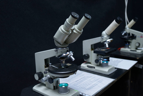 Mikroskope auf dem Arbeitstisch des Schullabors, schwarzer Hintergrund - Foto, Bild
