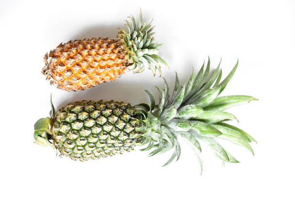 Grüne Ananas und orangefarbene Ananas isoliert in leuchtend gelbem Hintergrund, frisches tropisches Obst Hintergrund, Sommer / Urlaub, Essen und Trinken, saftig, kühl, vegan, gesunde Ernährung, Fitness - Foto, Bild