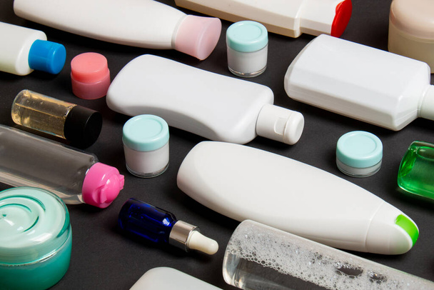 Vista superior de diferentes botellas de cosméticos y recipiente para cosméticos sobre fondo de color. Composición plana con espacio de copia. - Foto, imagen