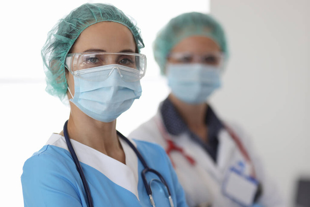 Портрет двух врачей в защитных медицинских масках, очках и перчатках - Фото, изображение