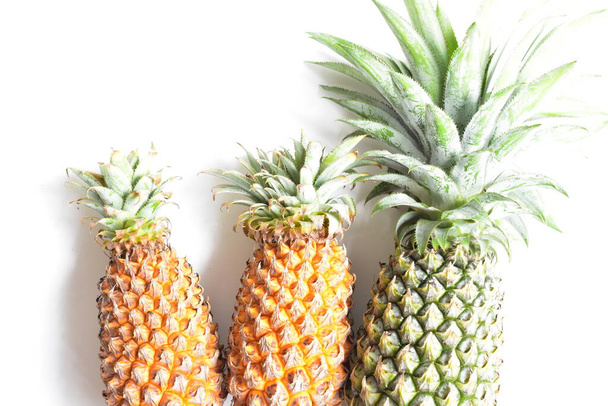 Green pineapple and orange pineapples isolated in bright yellow background, fresh tropical fruit background, summer/ holiday, food and beverage, juicy, cool, vegan, healthy food, fitness - Foto, afbeelding