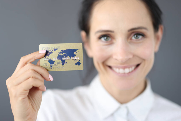 Retrato sonriente de una mujer de negocios que lleva una tarjeta bancaria de plástico en la mano - Foto, Imagen