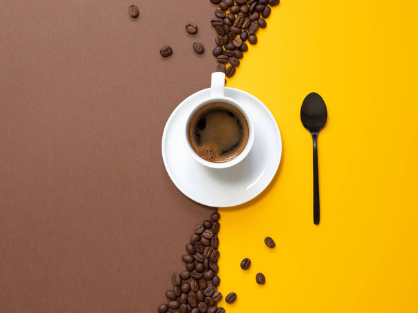 A cup of coffee on a brown background with copy space. Black espresso in a small mug with a spoon. Coffee concept. Top view. - Photo, image