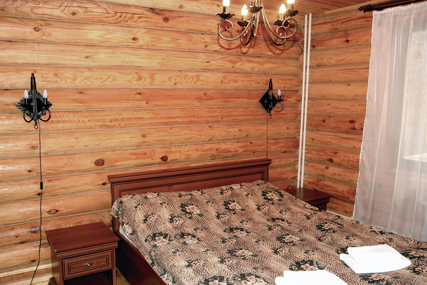 Einfache Einrichtung im Landhausstil in einem Holzhaus. Modernes rustikales Schlafzimmer mit Blockwänden - Foto, Bild