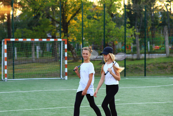 Two girls after lessons go in for tennis on the playground. - Foto, imagen