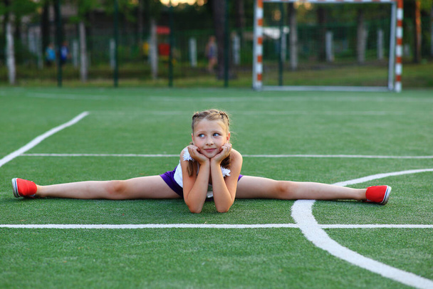 La chica se sienta en la cuerda en el campo de deportes - Foto, Imagen