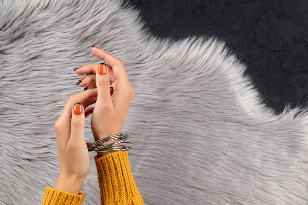 Las mujeres cuidadas entregan un fondo peludo. Moda otoño halloween naranja diseño de uñas. - Foto, imagen