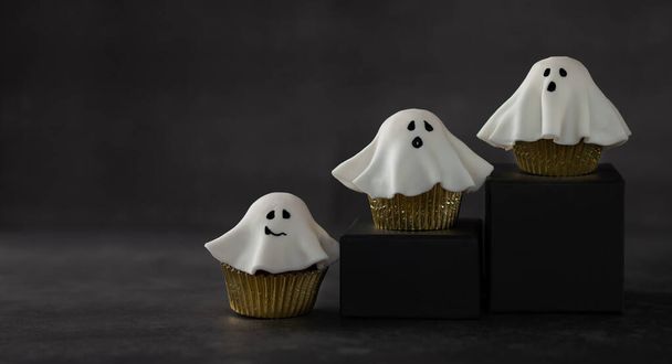 Halloween fondant ghost cupcakes on black podiums.  Halloween party food idea. - Foto, Imagem