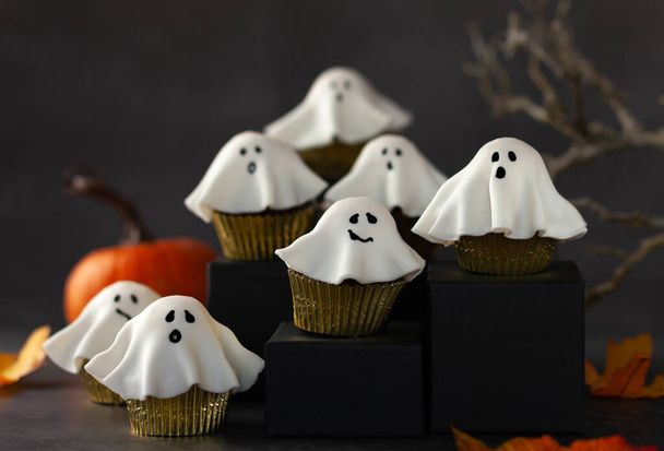 Halloween fondant ghost cupcakes on black podiums.  Halloween party food idea. - Foto, Imagem