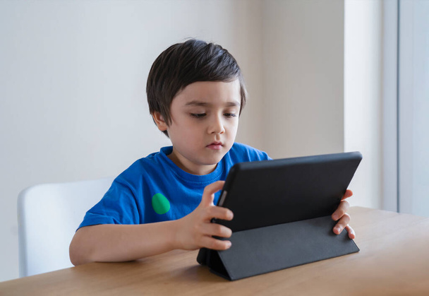 Neues normales Leben stlye Kid mit Tablet lernen Hausaufgaben, Kind mit digitalem Tablet für seine Online-Lektion zu Hause während der Quarantäne, Home School, Social Distance und E-Learning Online-Bildungskonzept - Foto, Bild