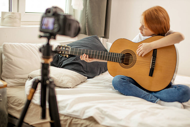sweet child girl blogger studying chords in acoustic guitar - Foto, Imagen
