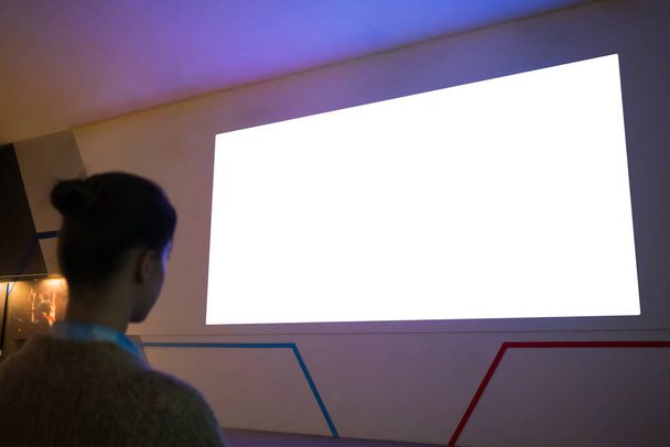 Woman looking at blank large interactive wall display - white screen concept - Photo, Image