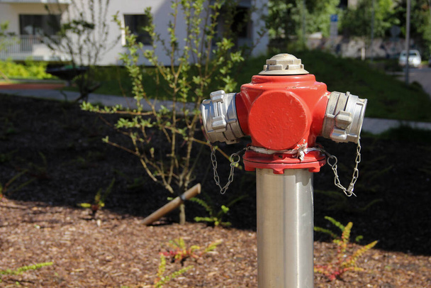 Пофарбований сталевий гідрант стоїть на газоні багатоповерхової квартири. Пожежний гідрант у громадському місці
.  - Фото, зображення