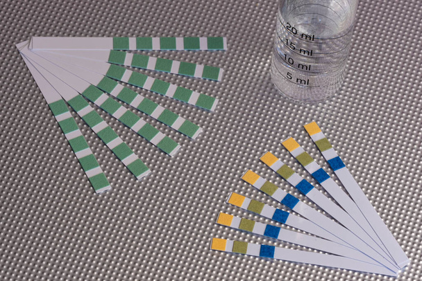 bandes d'analyse d'eau de différents types avec un tube gradué pour l'essai rempli d'eau sur une surface métallique texturée - Photo, image