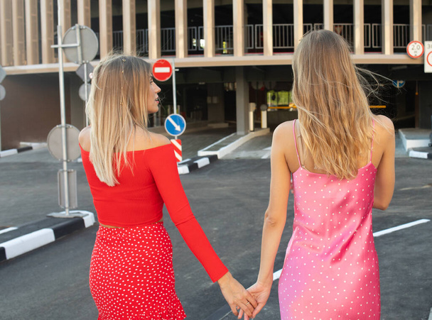Back view of two girl friends walking together on street. Blurred background. - Foto, Imagem