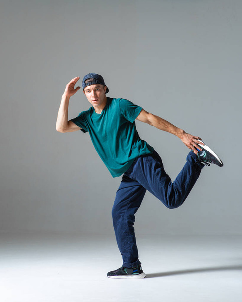 Cool guy breakdancer dancing in studio isolated on gray background. Breakdance lessons - Foto, Bild
